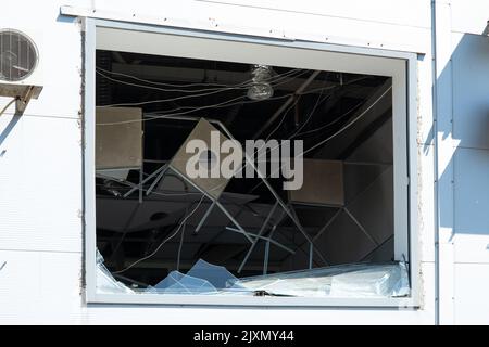 Kaputtes Einkaufszentrum nach Beschuss durch russisches Militär. Ergebnis der Raketenexplosion während des Krieges gegen die Ukraine. Gebrochene Fassade des Gebäudes, zerstöre Stockfoto