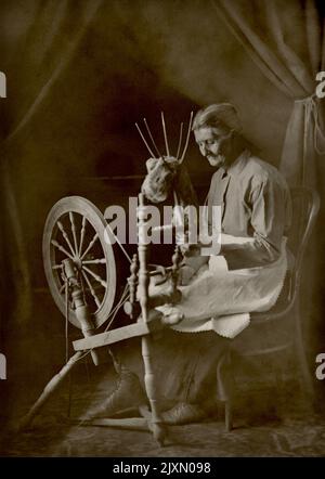 Spinning Wheel um 1900, alte Frau benutzt Spinning Wheel Stockfoto