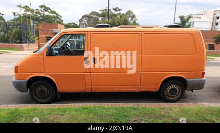 Seitenansicht des orangefarbenen Volkswagen Transporters, der auf der Straße geparkt ist Stockfoto