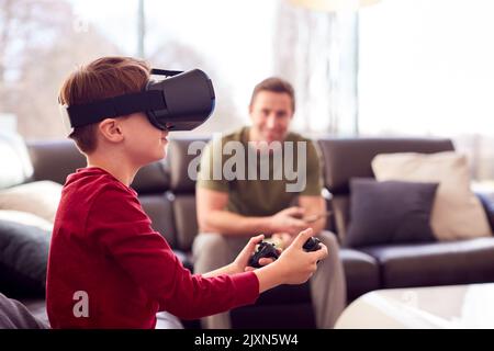 Vater Beobachten Sohn Tragen Virtual Reality Headset Spielen Sie Computer-Spiel Zu Hause Stockfoto