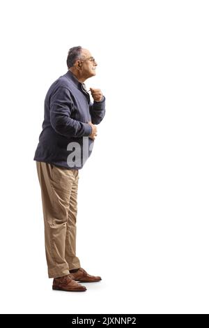 In voller Länge Profilaufnahme eines reifen Mannes, der sich fertig gemacht hat und seine Kleidung auf weißem Hintergrund isoliert sortiert Stockfoto