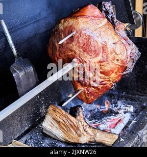 Der berühmte Prager Schinken wird über einem offenen Feuer auf einer Rotisserie gegrillt, bevor er von Touristen gegessen wird Stockfoto