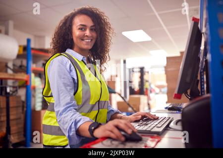 Porträt Einer Arbeiterin Im Geschäftigen Modernen Lagerhaus, Die Am Computerterminal Arbeitet Stockfoto