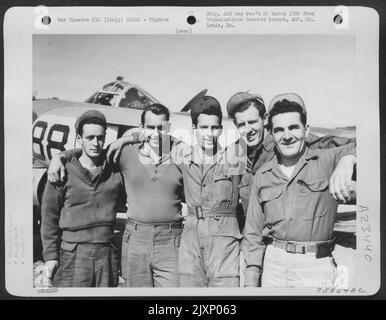 Die Bodenbesatzung der 94. Fighter Squadron, 1. Fighter Group, posiert neben ihrem Lockheed P-38 Lightning auf einem Flugplatz irgendwo in Italien. Stockfoto