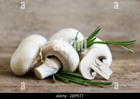 Champignon-Pilze auf Holzbrett mit Fichtenzweig Stockfoto