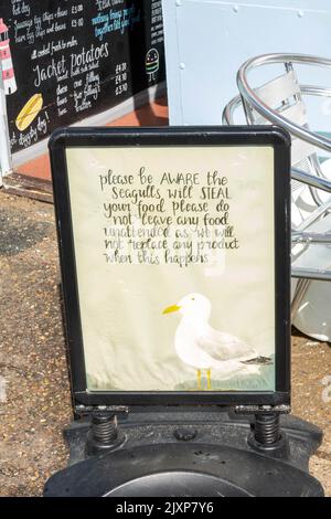 Ein Schild mit der Aufschrift, dass Sie sich davor hüten sollten, dass Möwen Lebensmittel vom Tisch stehlen und Ihren Tisch nicht unbeaufsichtigt lassen, wenn Essen serviert wird. Stockfoto