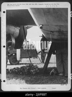 In der Bombenbucht dieses B-25 Mitchell-Bombers werden Cluster von Splitterbomben geladen, während hochoktaniges Gas in die Tanks gepumpt wird. Mitchells von der AAF von 12. verwendete diese „Frags“ mit großer Wirksamkeit gegen die Konzentration deutscher Truppen Stockfoto