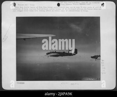 Mehr als dreißig Flakausbrüche von deutschen Flak-Geschützen sind auf diesem Foto zu sehen, das einen Teil einer Formation nordamerikanischer B-25 Mitchell-Mittelbomber der Northwest African Air Forces zeigt, die gerade ihre Bomben mit aufschlussvoller Wirkung abgeworfen hatten Stockfoto