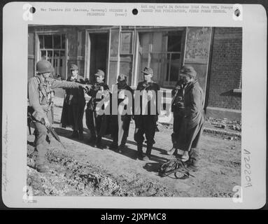 Einige der ersten deutschen Soldaten, die in Aachen gefangen genommen wurden, stehen unter dem Kommando eines amerikanischen Soldaten. Die Gefangenen wurden während eines Bombardements der Stadt durch Artillerie und Tauchbomber der Neunten Luftwaffe gefangen genommen. Stockfoto