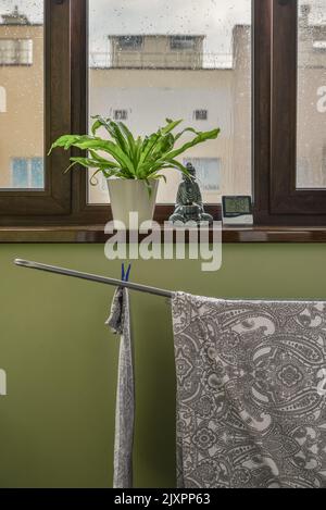 Bettwäsche auf dem Wäscheständer mit digitalem Temperatur- und Feuchtigkeitssensor auf dem Balkon an einem regnerischen Tag Stockfoto