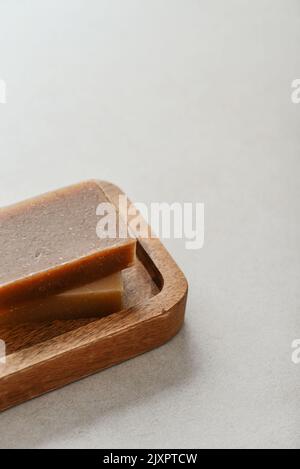 Natürliche handgemachte Seifenstücke auf Holztablett auf hellem Beton-Hintergrund Stockfoto