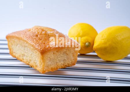 Hausgemachter Zitronenlizzle Brotbackblechkuchen auf einem Edelstahlgestell mit Zitronen Stockfoto
