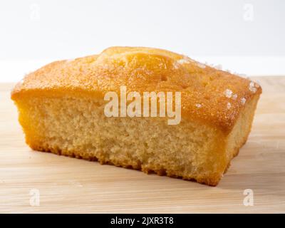 Auf einem Bambusbrett isolierter Kuchen mit Zitronentrieselregen aus Brotbackform Stockfoto
