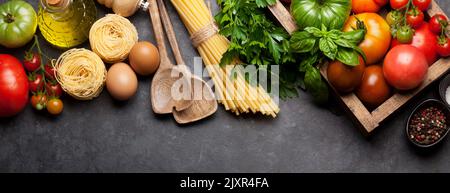 Nudeln, Tomaten und Kräuter. Kochzutaten auf Steintisch. Draufsicht flach liegend Stockfoto