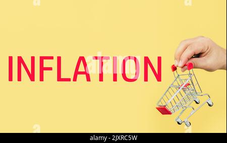 Männliche Hand mit kleinem leeren Warenkorb. Inflation, steigende Lebensmittelpreise und steigende Kosten für Supermarktwaren Stockfoto