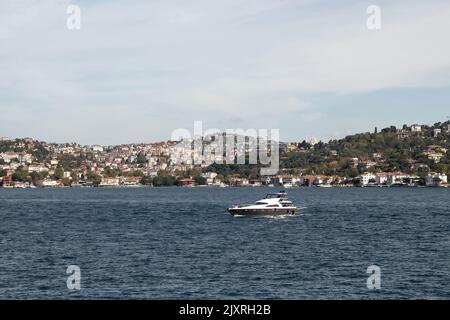 Blick auf eine Yacht, die auf dem Bosporus und der asiatischen Seite Istanbuls vorbeifährt. Es ist ein sonniger Sommertag. Wunderschöne Reiseszene. Stockfoto