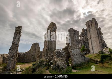 corfe Castle in dorset uk unter einem grauen und bewölkten bedrohlichen und atmosphärischen Himmel, unheimliche Aussicht auf corfe Castle, halloween-Stil launische Bild corfe Castle. Stockfoto