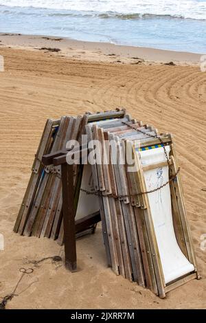 Stapel von traditionellen Holzliegen am Sandstrand von swanage in dorset, Holzliegen am Meer für die Wintersaison gestapelt., Strand Stockfoto