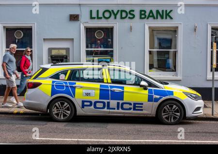 Polizist, der die diensthabende Bank sieht, Polizeiauto vor der Bank geparkt, lloyds Bank High Street Branch, Nachlassauto in Polizeikizzen, dorset Polizeiauto. Stockfoto