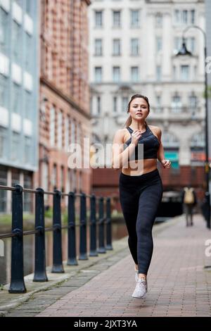 Eine alleinstehende Joggerin auf den Straßen von Manchester, Großbritannien Stockfoto