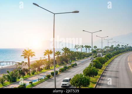 Straße am Meer entlang vom Flughafen Gazipasa nach Alanya, Türkei bei Sonnenuntergang. Stockfoto