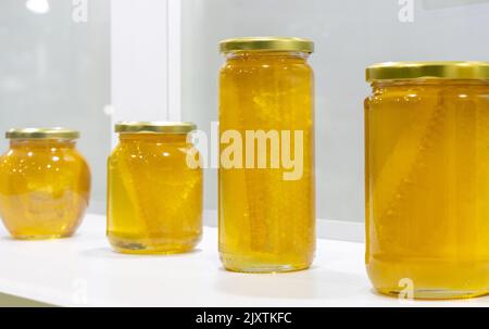 Honig in Gläsern auf weißem Hintergrund Stockfoto