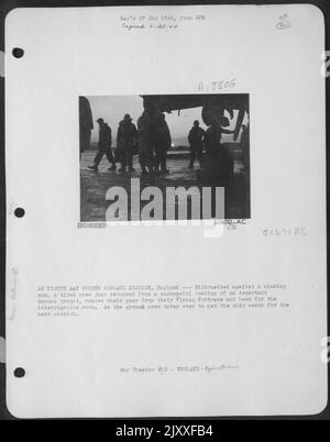 EINE ACHTE BOMBERKOMMANDATIONSSTATION der AAF, England - eine müde Besatzung, die vor einer sinkenden Sonne geschildet wurde, ist gerade von einem erfolgreichen Bombenangriff auf ein wichtiges deutsches Ziel zurückgekehrt, nimmt ihre Ausrüstung von ihrer Flying Ofrtress und geht in den Verhörraum. Stockfoto