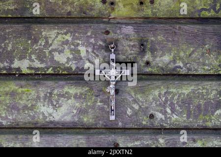 Kruzifix hängt an einer schäbigen Holzwand Stockfoto