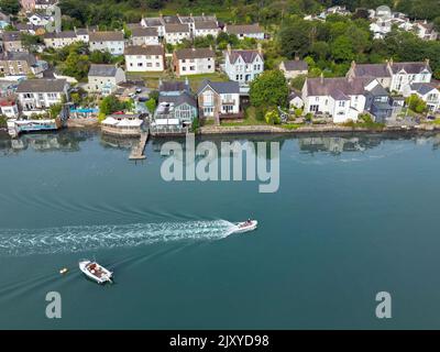 St Dogmael's, Pembrokeshire, Wales - August 2022: Luftaufnahme eines kleinen motorisierten Schlauchbootes, das am Ferry Inn Pub und den Häusern am Wasser vorbeifährt Stockfoto