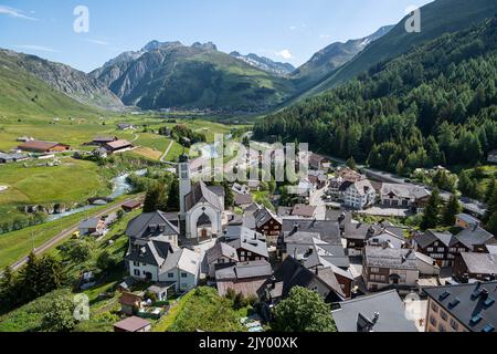 Das Dorf Hospental in den Schweizer Alpen (Schweiz), Andermatt im Hintergrund Stockfoto