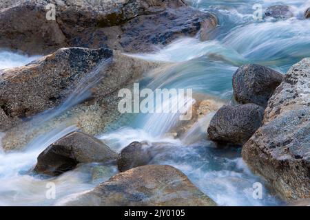 Langzeitbelichtung des fließenden Wassers eines Baches in den Schweizer Alpen Stockfoto