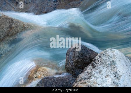 Langzeitbelichtung des fließenden Wassers eines Baches in den Schweizer Alpen Stockfoto