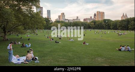 Menschen in Central Park, Manhattan, New York City, USA am Ende eines Sommertages Stockfoto