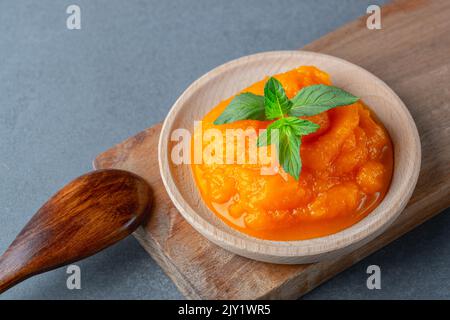 Kürbis- und Karotten-Baby-Püree in einer runden Schale isoliert auf grauem Hintergrund Stockfoto