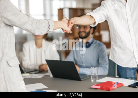 Nahaufnahme des Vorgesetzten, der einem neuen Teammitglied die Hand schüttelt, der ihn für eine Stelle auf der Mitarbeiterbesprechung einwirbt Stockfoto