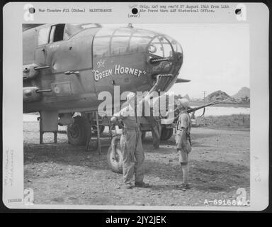 Ein Mitglied der Bodenbesatzung, die die nordamerikanische B-25 „The Green Hornet“ betankt, spricht mit der chinesischen Garde, die bei einem Luftwaffenstützpunkt 14. in Kweiline, China, neben dem Flugzeug steht. 2. August 1944. Stockfoto