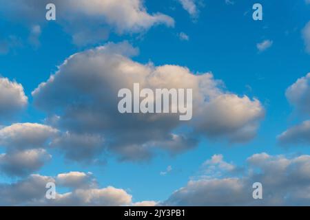 Weiße und dunkle, flauschige Wolken am blauen Himmel. Hintergrund aus Wolken. Stockfoto