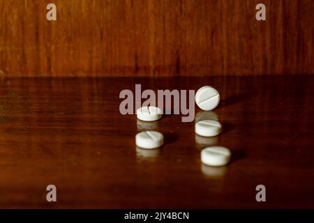 Einfacher Stapel weißer Pillen, Medikamente, Pillen auf braunem Hintergrund gestapelt. Medizinische Versorgung. Stockfoto
