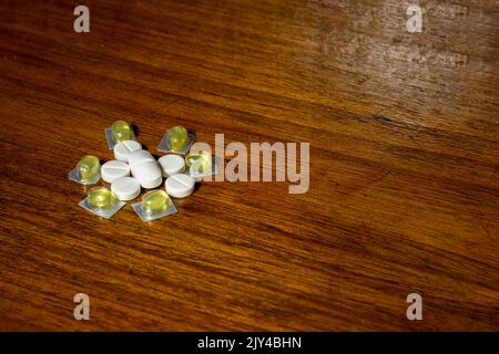 Einfacher Stapel weißer und gelber Pillen, Medikamente, Pillen auf braunem Hintergrund gestapelt. Medizinische Versorgung. Stockfoto