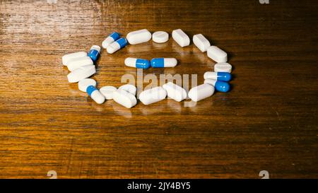 Einfacher Stapel weißer und blauer Pillen, Medikamente, Pillen auf braunem Hintergrund gestapelt. Medizinische Versorgung. Stockfoto