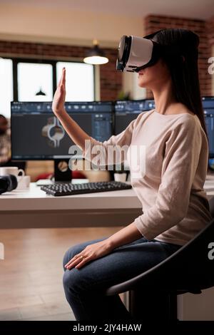 Asiatischer Techniker mit vr-Gläsern, die Produkte entwickeln und bei der Produktion von Industriemaschinen helfen. CAD-Ingenieur, der Zahnradmodelle mit Virtual Reality 3D-Headset und -Software fertigt. Stockfoto