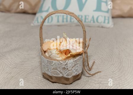 Der Korb ist voller Blütenblätter, die in der Hochzeitszeremonie vom Blumenmädchen verteilt werden. Stockfoto