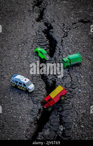 Bunte Auto Spielzeug auf einem geknackten Asphalt Stockfoto