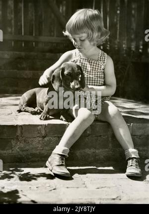 Vintage kleines Mädchen und Hund, süßes Mädchen mit Hund, Dachshund Stockfoto