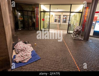 München, Deutschland. 08. September 2022. Ein Obdachloser schläft in den frühen Morgenstunden vor einer Zweigstelle der City Savings Bank im Stadtzentrum. Kredit: Peter Kneffel/dpa/Alamy Live Nachrichten Stockfoto