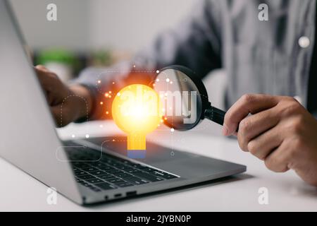 Entdecken Sie das Konzept der Geschäftsaussichten, und Geschäftsleute untersuchen eine Glühbirne mit einer Lupe. Ideen für neue Geschäfte. Stockfoto