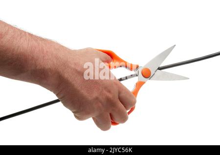 Menschliche Hand mit einer Schere schneidet einen schwarzen Draht Stockfoto