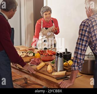 Kochen mit Liebe liefert Nahrung für die Seele. Eine Frau, die einen Kochkurs anleitet. Stockfoto