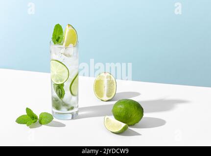 Eis und Mojito im Glas liegen mit starkem Schatten auf dem Tisch Stockfoto