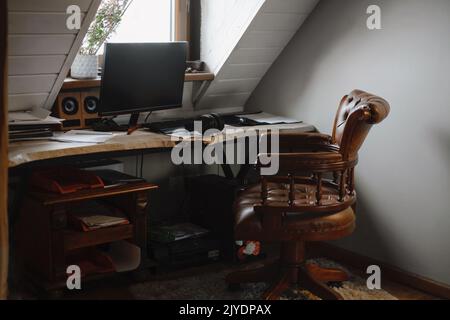 Freiberuflicher Arbeitsplatz, Heimarbeitsplatz mit Computer und Bildschirm. Komfortabler Schreibtisch ohne Personen mit Heimplanze und Lampe. Boho Vintage Stuhl von The Stockfoto